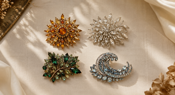 Four vintage rhinestone brooches for fire, earth, air and water on warm ivory fabric